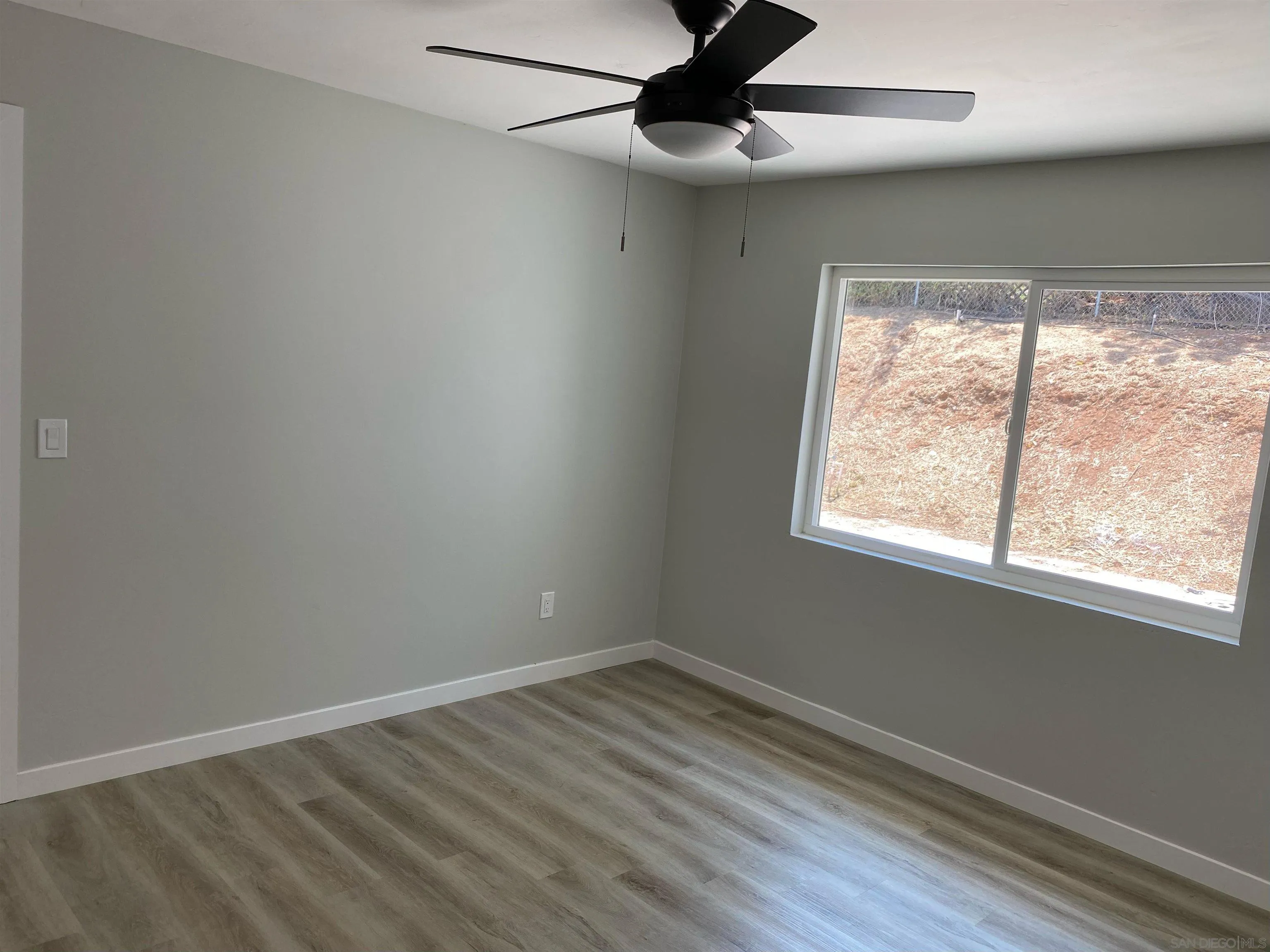 3866 Spring Drive Spring Valley, CA 91977 - Photo 8 of 9 an empty room with wooden floor fan and windows