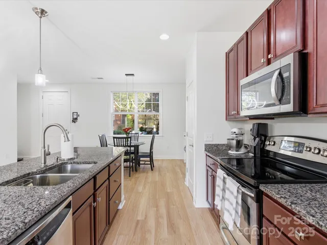 a kitchen with granite countertop a sink a stove cabinets and dining table