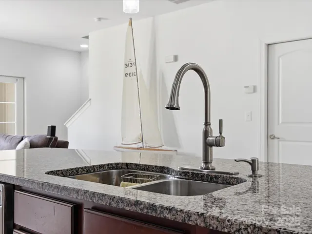 a kitchen with a granite countertop sink and refrigerator