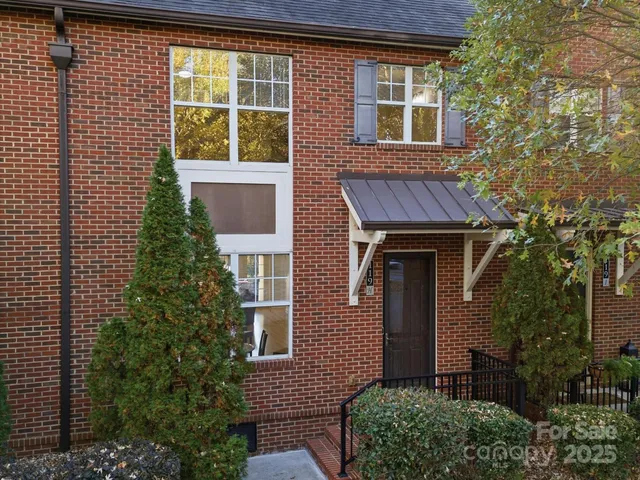 a view of a brick house with a large windows and flower plants