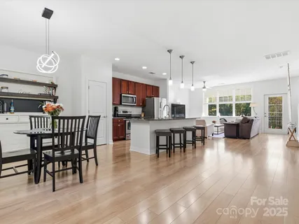 a view of a dining room and livingroom with furniture wooden floor a rug a fireplace and a chandelier
