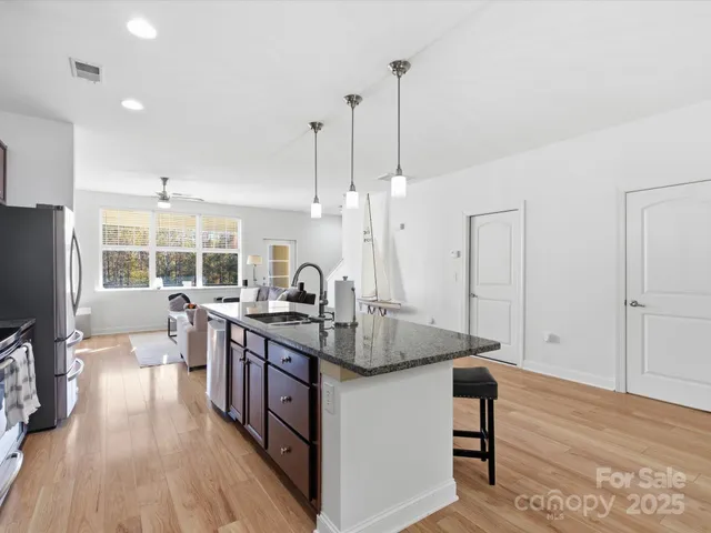 a kitchen with stainless steel appliances granite countertop a sink a stove and a wooden floors