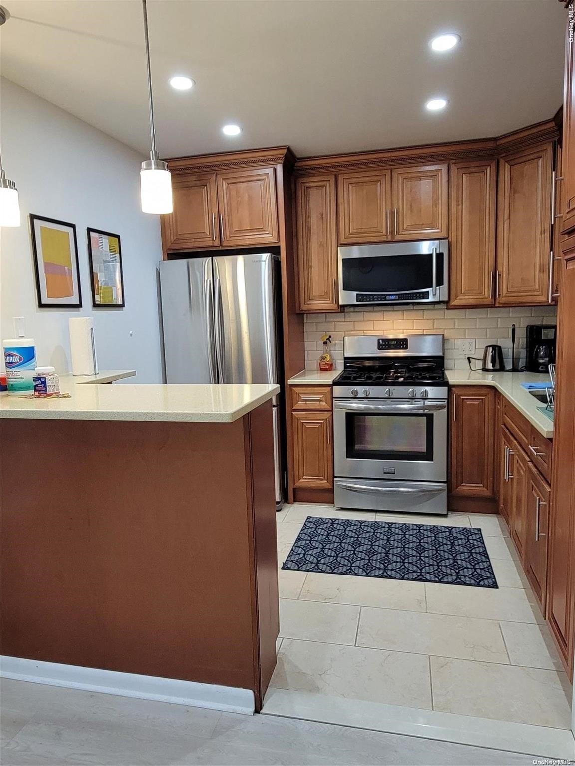 85-19 75th Street Queens, NY 11421 - Photo 11 of 17 a kitchen with stainless steel appliances granite countertop a refrigerator a stove a sink a microwave and wooden cabinets
