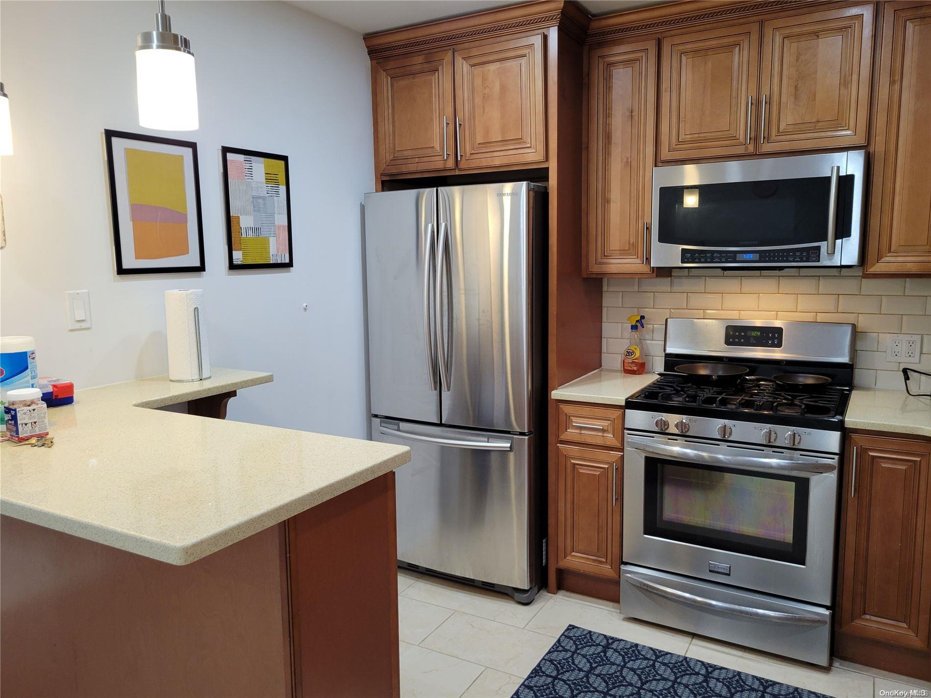 85-19 75th Street Queens, NY 11421 - Photo 12 of 17 a kitchen with stainless steel appliances a stove a microwave and a refrigerator