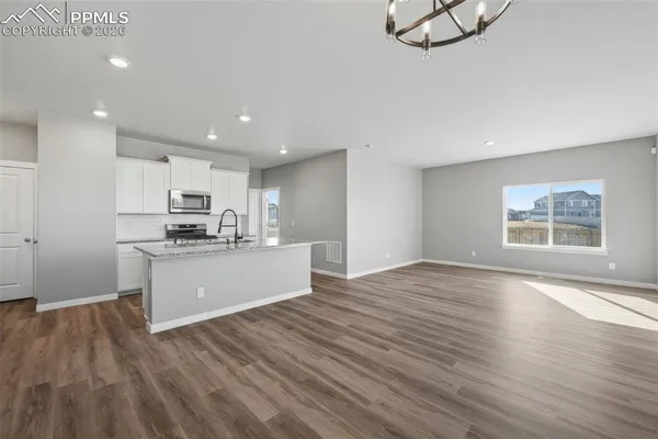 a view of kitchen with kitchen island wooden floor appliances and cabinets