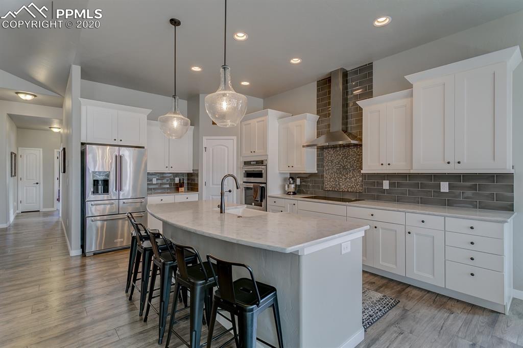 16430 Dancing Bear Lane Monument, CO 80132 - Photo 13 of 50 a kitchen with stainless steel appliances kitchen island granite countertop a table chairs sink and cabinets