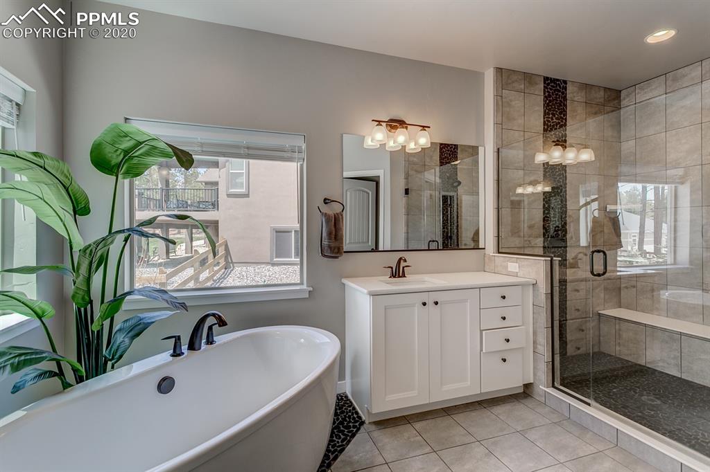 16430 Dancing Bear Lane Monument, CO 80132 - Photo 24 of 50 a bathroom with a double vanity sink a mirror and a bathtub