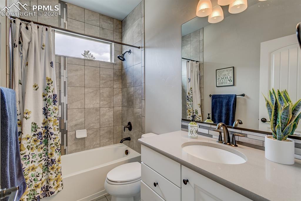 16430 Dancing Bear Lane Monument, CO 80132 - Photo 33 of 50 a bathroom with a granite countertop sink a toilet a mirror a vanity a bath tub and shower