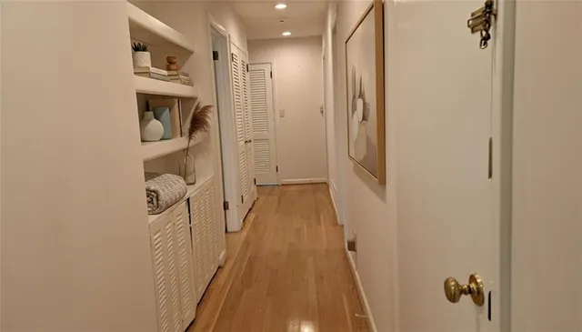 a view of a hallway with wooden floor and a bathroom