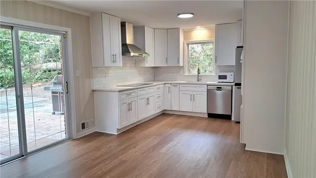 a kitchen with stainless steel appliances granite countertop wooden floors a stove a sink and a window