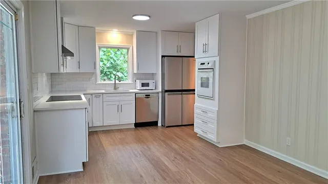 a kitchen with a refrigerator a sink and dishwasher with wooden floor