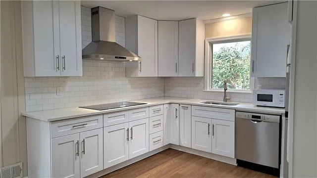 a kitchen with white cabinets appliances a sink and a window