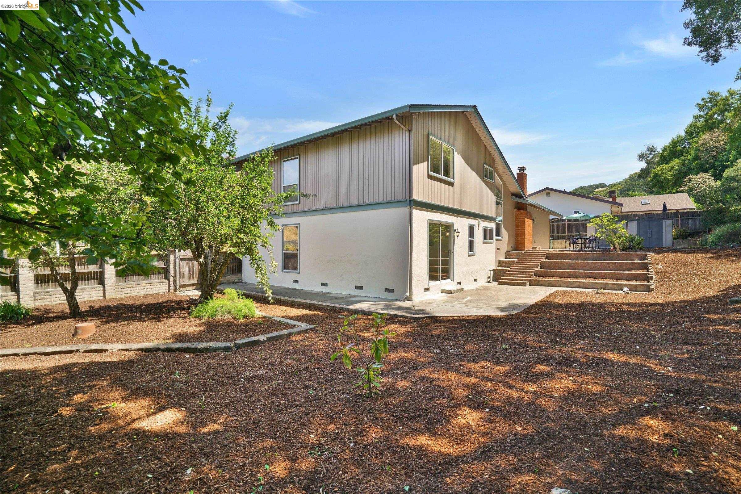 2826 Wright Avenue Pinole, CA 94564 - Photo 53 of 70 Rear exterior featuring a multi-level patio with steps, wood chip ground cover, and mature trees