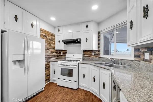 a kitchen with stainless steel appliances granite countertop a refrigerator sink and stove