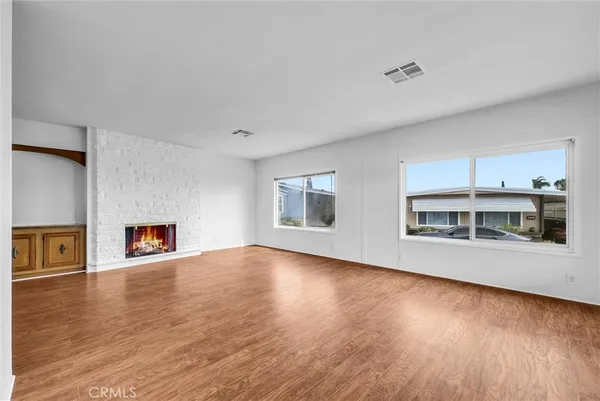 a view of a big room with wooden floor fire place and windows