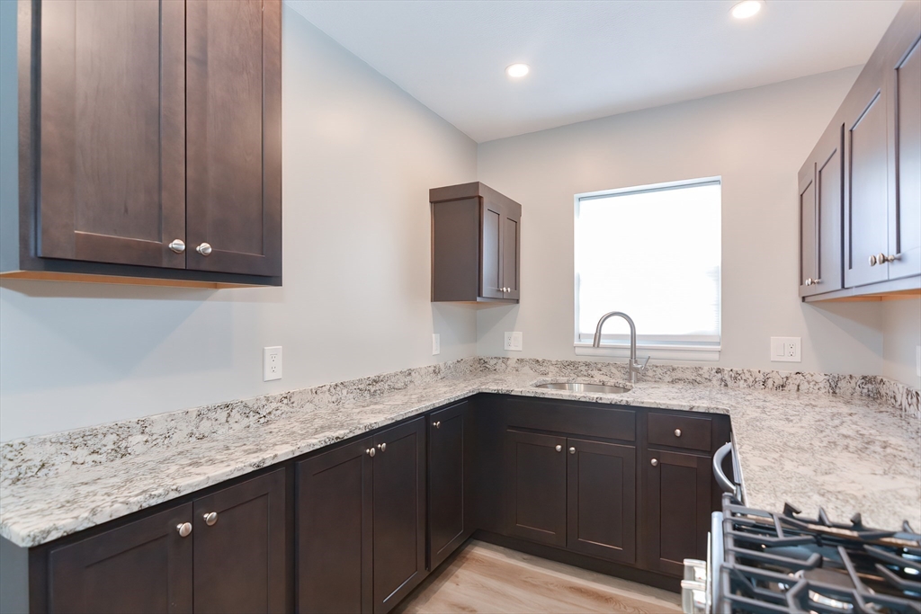 149 Lake Shore Road, Unit 2 Boston, MA 02135 - Photo 5 of 38 a kitchen with granite countertop a sink stainless steel appliances and cabinets