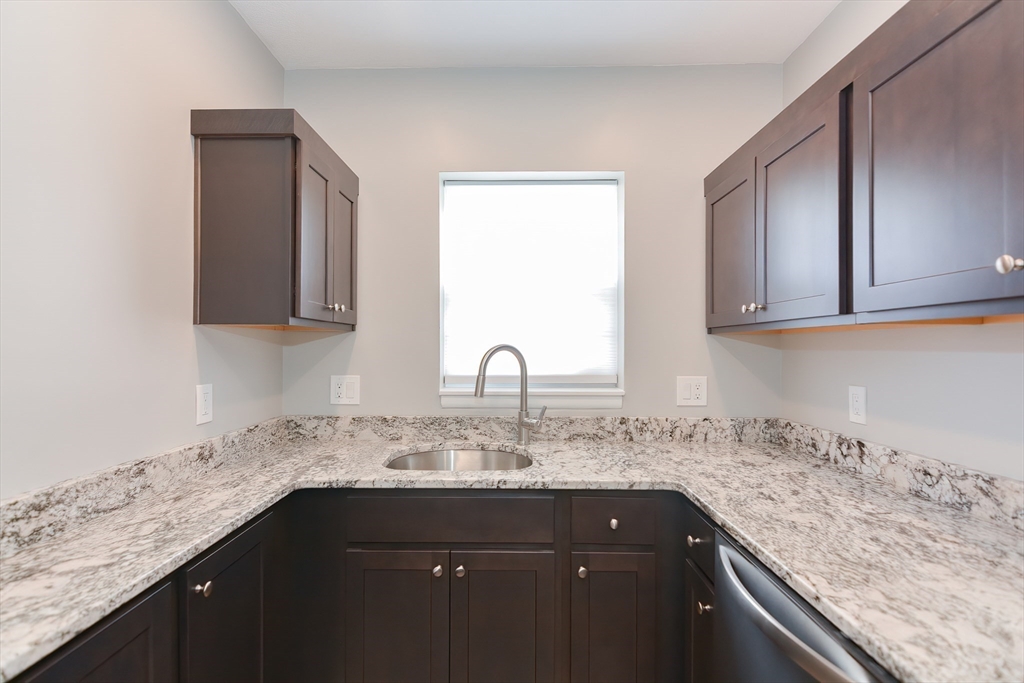 149 Lake Shore Road, Unit 2 Boston, MA 02135 - Photo 6 of 38 a sink with granite countertop white cabinets and a granite counter top