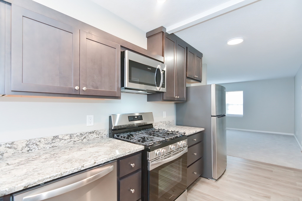 149 Lake Shore Road, Unit 2 Boston, MA 02135 - Photo 8 of 38 a kitchen with stainless steel appliances granite countertop a sink stove and microwave