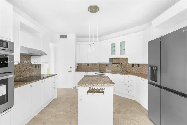 a kitchen with stainless steel appliances kitchen island granite countertop a stove a sink and a microwave