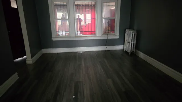 a view of wooden floor in an empty room with a window