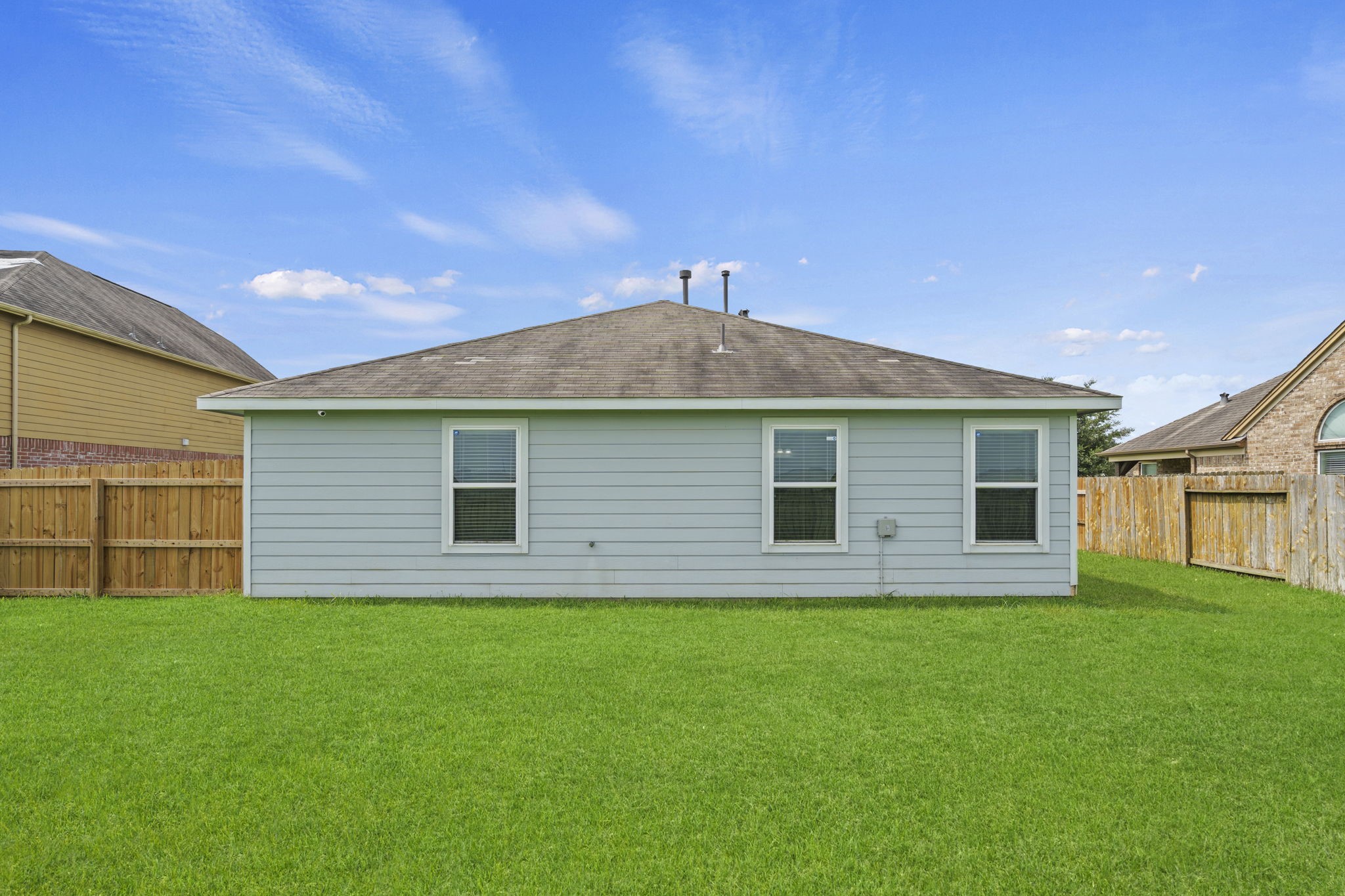 2110 Red Cedar Trail Rosenberg, TX 77471 - Photo 15 of 20 A pristine, single-story rear exterior boasting an extensive, manicured grassy yard. The property is framed by solid wood privacy fences on the side perimeters, making it ideal for pets and outdoor activities.