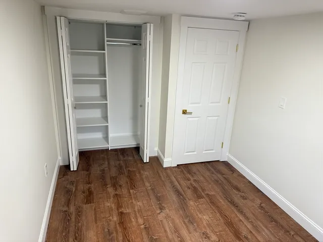 an empty room with wooden floor closet and windows