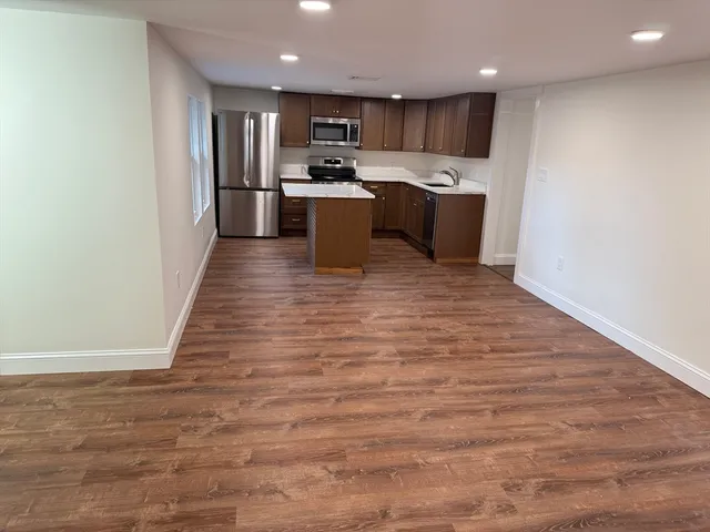 a view of kitchen with kitchen island a sink wooden floor and a refrigerator