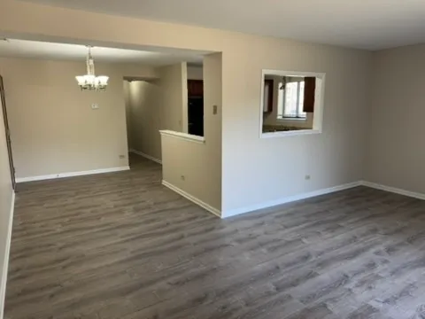 a view of a hallway with wooden floor and a living room