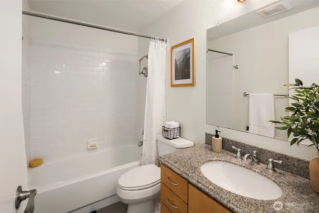 a bathroom with a granite countertop sink toilet and shower