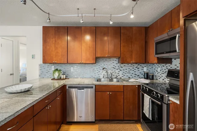 a kitchen with stainless steel appliances granite countertop a stove a sink and a microwave