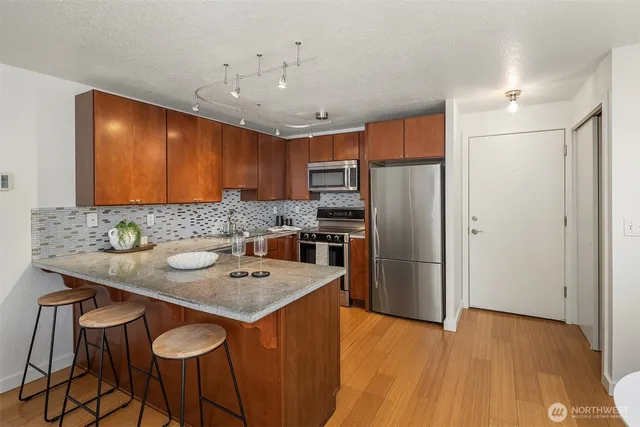 a kitchen with stainless steel appliances granite countertop a refrigerator a sink and a stove