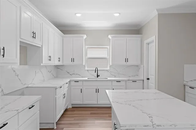 a kitchen with white cabinets sink and stove