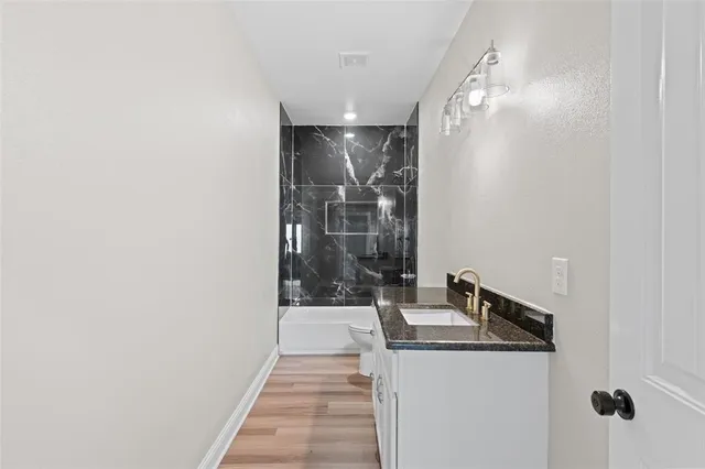 a bathroom with a granite countertop sink a toilet and shower