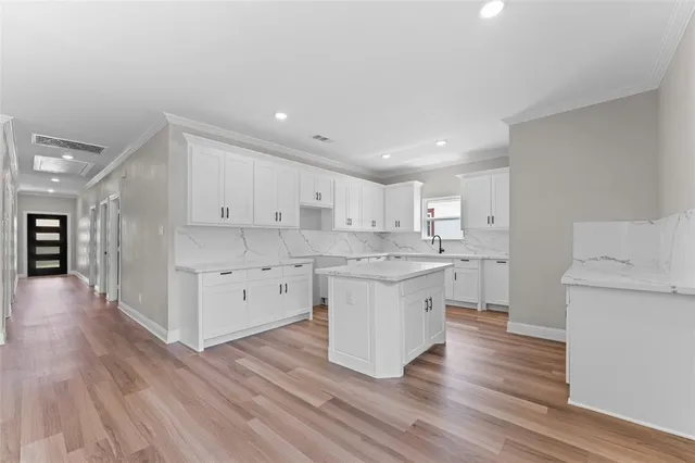 a large kitchen with a lot of counter space and wooden floor