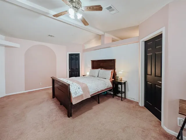 a bedroom with a bed lamp and a ceiling fan