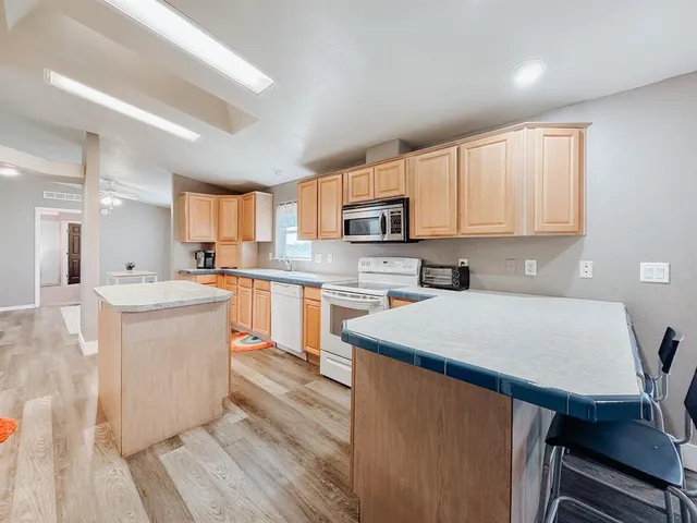 a kitchen with a sink a stove a refrigerator cabinets and a dining table