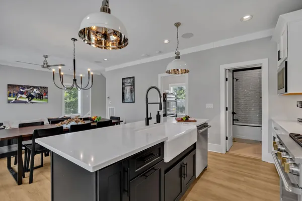 a kitchen with a stove a kitchen island a sink dishwasher a dining table and chairs with wooden floor