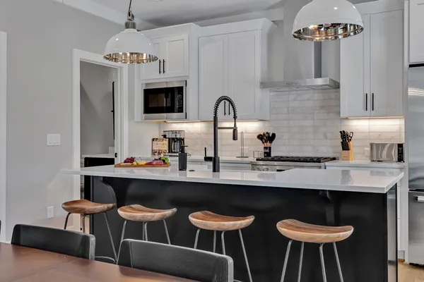 a kitchen with stainless steel appliances a dining table chairs and a refrigerator