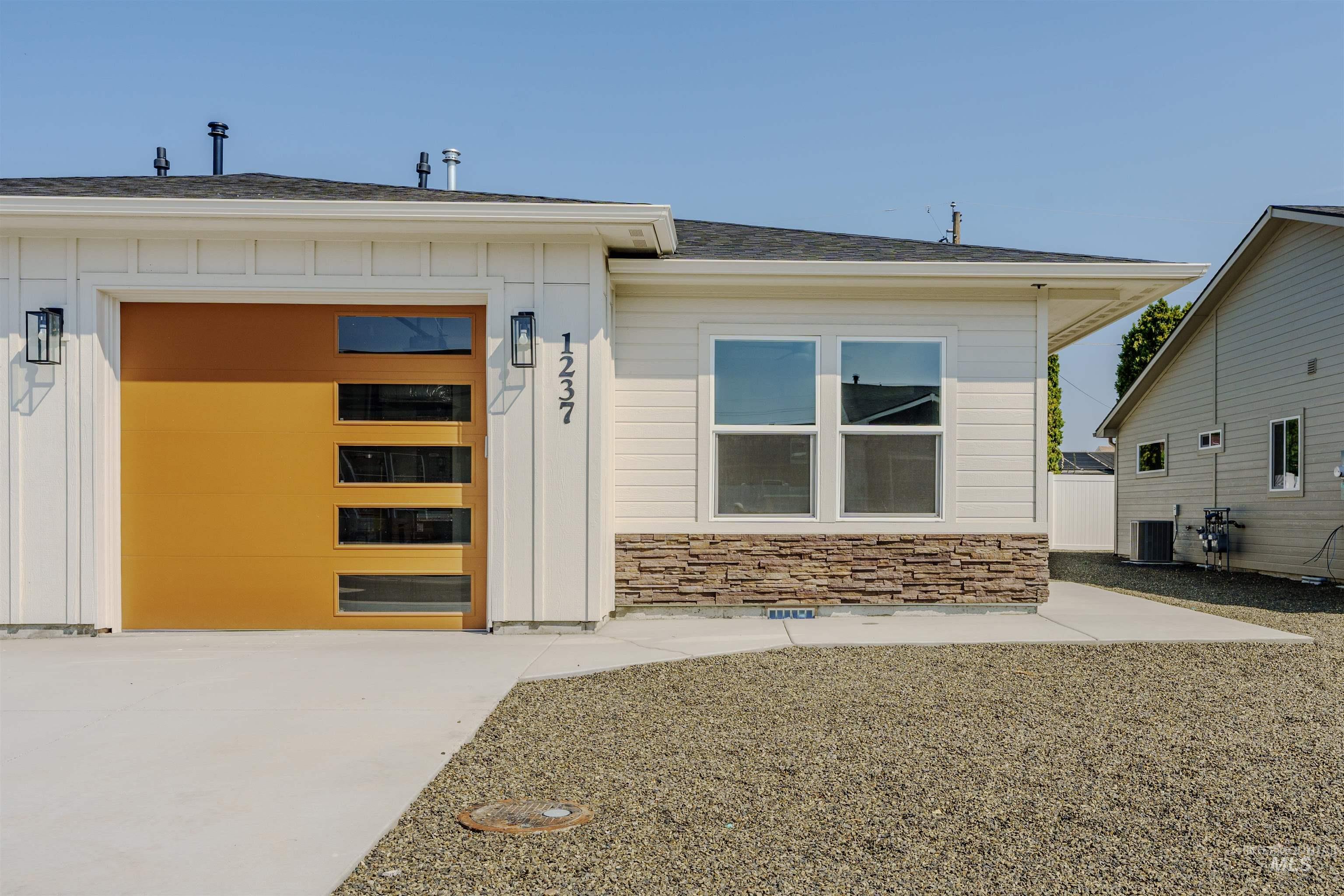 1237 Phillips Circle Ontario, OR 97914 - Photo 1 of 1 Entrance to property featuring board and batten siding, stone siding, an attached garage, a shingled roof, and concrete driveway