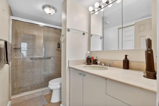 a bathroom with a granite countertop sink a toilet and shower