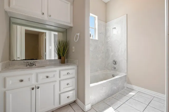 a bathroom with a granite countertop sink a mirror and a bathtub
