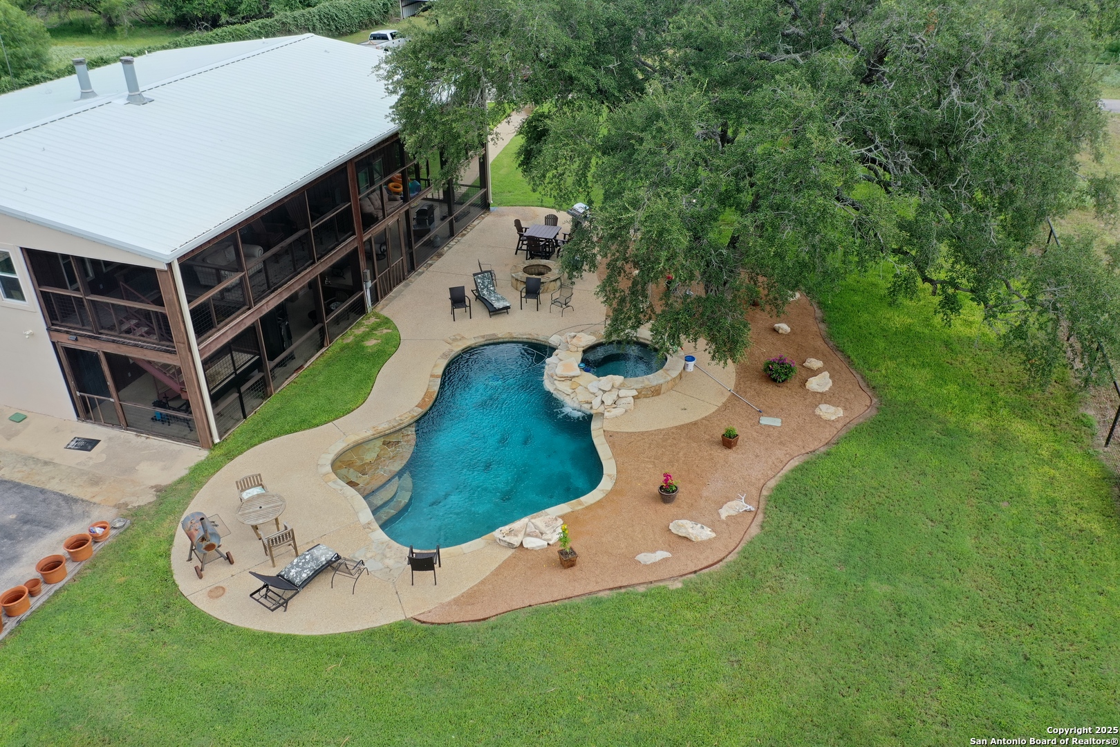 an aerial view of a backyard with table and chairs a barbeque and a lawn chairs