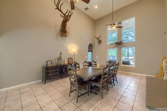 a dining room with chandelier fan and wooden floor