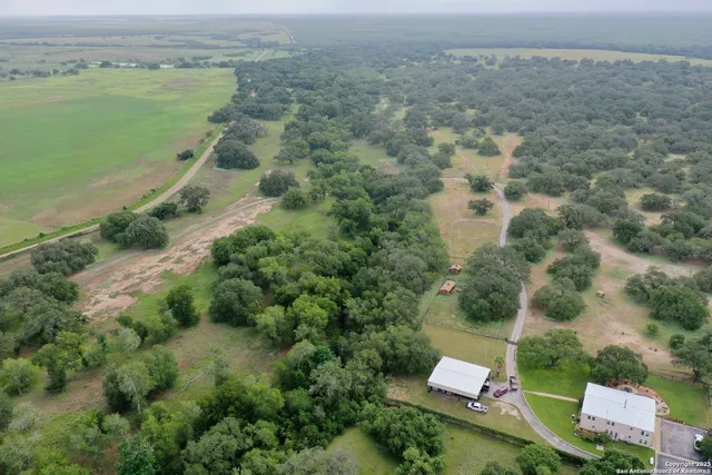 an aerial view of residential houses with outdoor space and trees