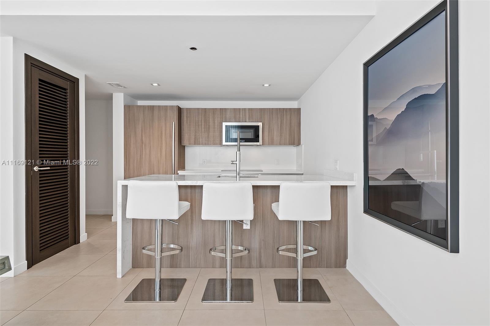401 North Birch Road, Unit TH7 Fort Lauderdale, FL 33304 - Photo 8 of 29 a kitchen with a dining table chairs and white cabinets