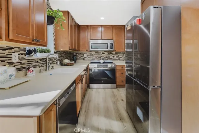 a kitchen with a sink a counter top space stainless steel appliances and cabinets