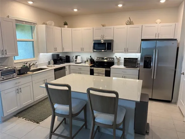 a kitchen with stainless steel appliances a table chairs microwave and refrigerator a sink