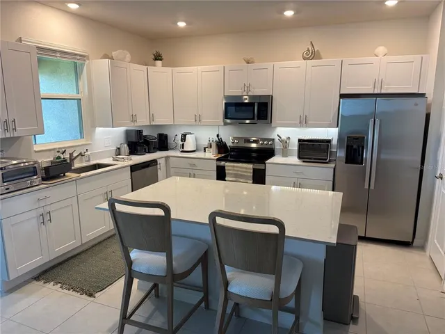 a kitchen with stainless steel appliances a table chairs microwave and refrigerator a sink