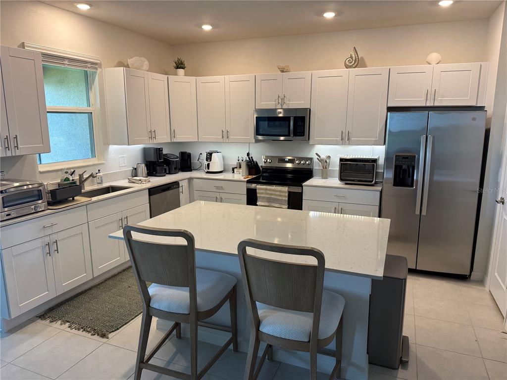 9276 Bonita Mar Drive Parrish, FL 34219 - Photo 2 of 54 a kitchen with stainless steel appliances a table chairs microwave and refrigerator a sink