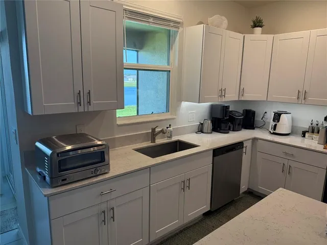 a kitchen with stainless steel appliances granite countertop a sink a stove and white cabinets